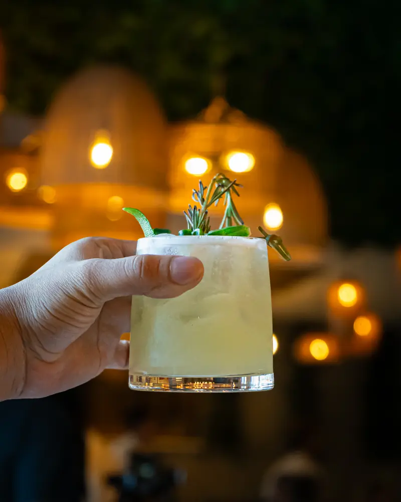 A cocktail glass held up against warm bar lights