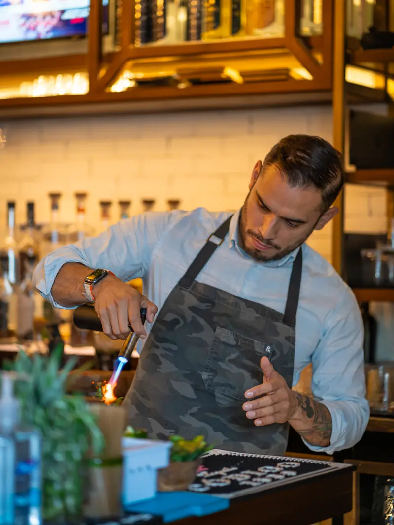 Bartender at work behind the bar under warm lights