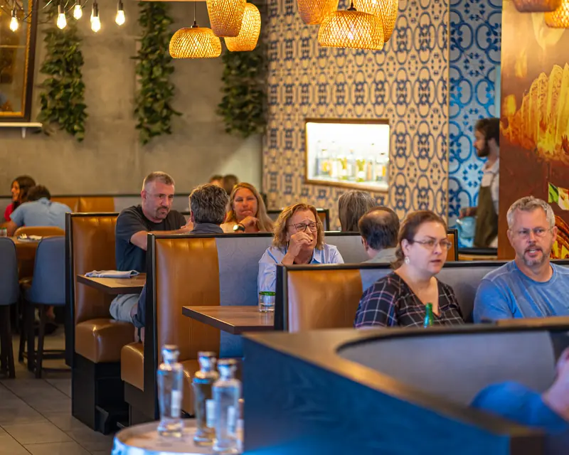 Guests in tan leather booths beneath woven pendant lights and blue patterned tile