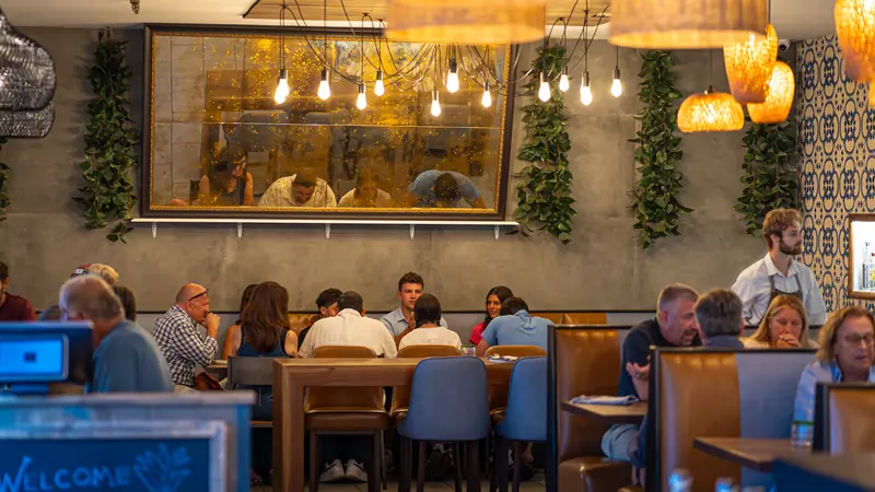 The dining room with a long communal table under hanging Edison bulbs