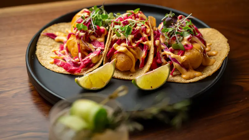 Fish tacos topped with pink cabbage slaw and chipotle crema, with lime