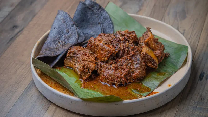 Braised beef on a banana leaf with blue corn tortilla chips