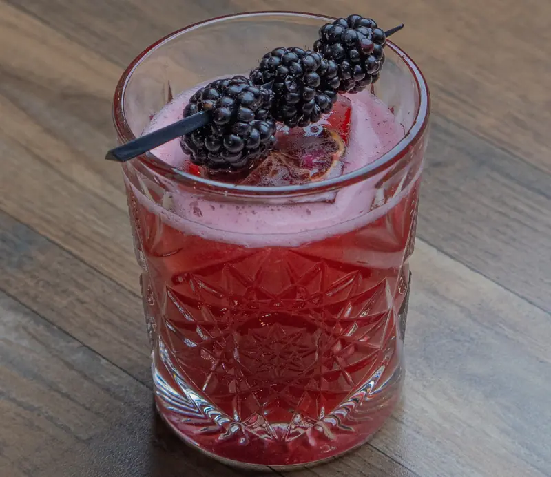A blackberry cocktail with fresh blackberries on a skewer