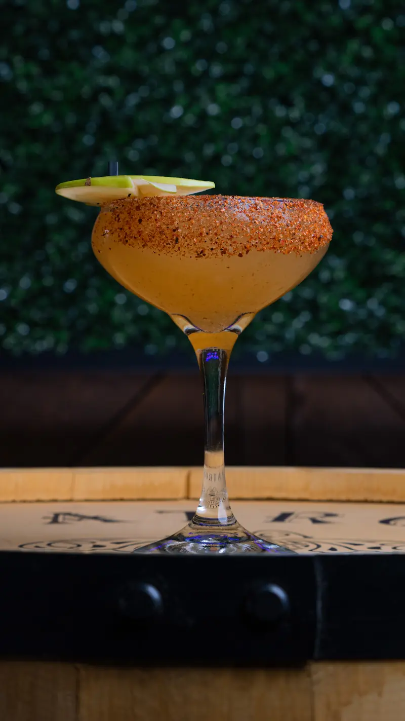 A chili-rimmed margarita in a coupe on a barrel top