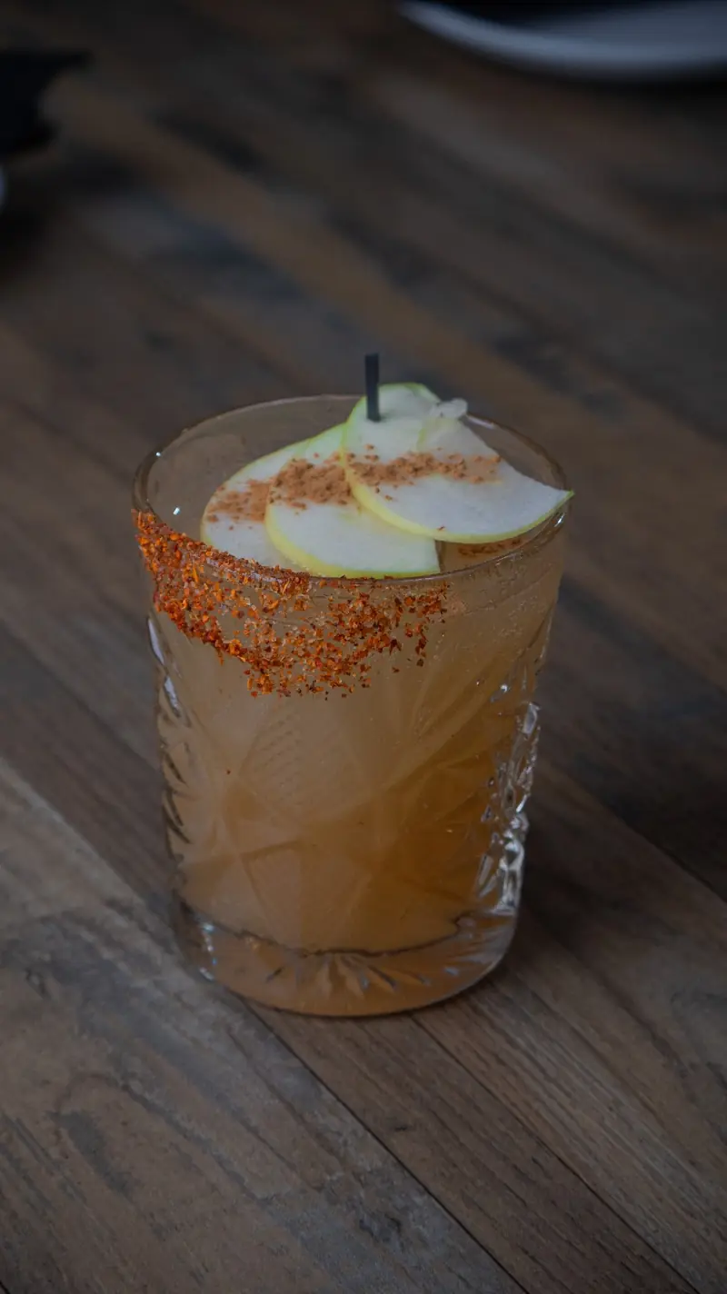 A pear cocktail with a chili-salt rim over ice